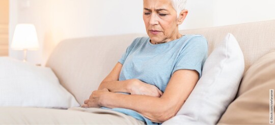 Ältere Frau auf einer Couch mit Beschwerden wegen einer chronischen Blasenentzündung