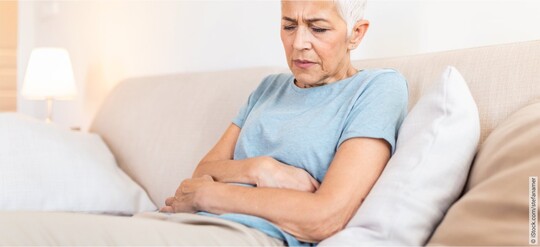 Ältere Frau auf einer Couch mit Beschwerden wegen einer chronischen Blasenentzündung