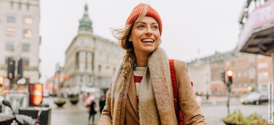 Gepan® Mannose to go von Pohl-Boskamp stärkt Dein Immunsystem Glücklich scheinende, lachende Frau, bei schlechtem Wetter in einer Stadt